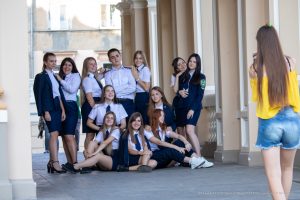 Фотография группы студентов в форме, позирующих для уличного фотографа на фоне архитектурного здания.