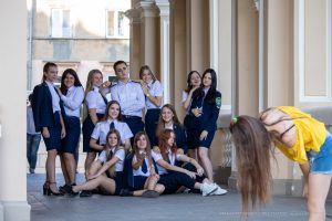 Фотография группы студентов в форме, позирующих для уличного фотографа на фоне архитектурного здания.