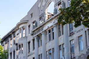 Фото разрушенного здания с поврежденными стенами и окнами. Контраст между разрухой и голубым небом.