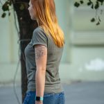 Фотография девушки с татуировкой цветка на руке. Татуировка выполнена в черных тонах и имеет детализированный рисунок.