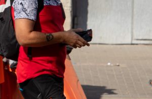 Фото тату на руке мужчины. Чёрный минималистичный рисунок, предположительно, в виде буквы или символа.