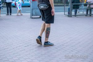 Фотография татуировки на голени мужчины, выполненной в ярких цветах. Рисунок виден в профиль, когда мужчина идет по улице.