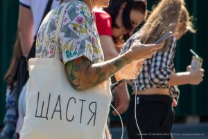 Крупный план татуировки на руке девушки, изображающей цветочный узор и абстрактные элементы. Девушка держит телефон.