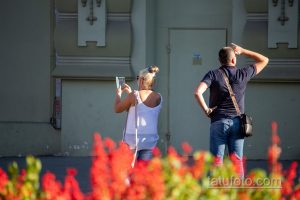 Фото пары, где у обоих есть татуировки. У мужчины тату на предплечье, у женщины - на плече. Общий вид, уличная фотография.