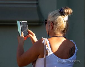 Фото тату на лопатке женщины, вид сзади. Виден фрагмент рисунка татуировки, предположительно, цветочный мотив.