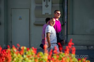 Фото тату на руке мужчины, идущего по улице. Видна часть татуировки в стиле графика, выполненной черными чернилами.