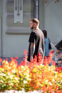 Фото тату: рука мужчины с татуировкой карпа кои в ярких цветах и цветами. Детализированный рисунок и динамичная композиция.