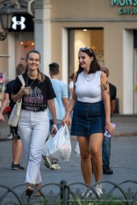 Фото тату на плече девушки, идущей по улице. Татуировка выполнена в минималистичном стиле, изображает силуэт человека.