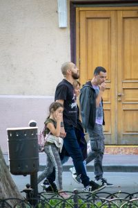 Фото тату на предплечье мужчины, идущего с семьей по улице. Рисунок татуировки выполнен в черных тонах, изображает абстрактный узор.