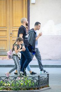 Фотография мужчины и девочки, идущих по улице. У мужчины на предплечье видна татуировка с изображением черепа и других элементов.