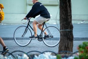 Фото тату на ноге мужчины: небольшая татуировка, черный цвет, минималистичный рисунок, татуировка на икре, современный стиль.