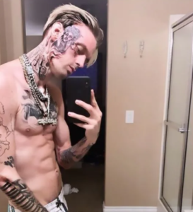 Фотография Post Malone с многочисленными татуировками на лице, шее и руках, демонстрирующая его провокационный стиль.