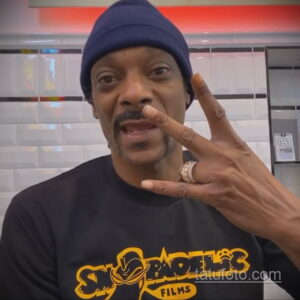 Крупный план Snoop Dogg с новой татуировкой на руке и в синей шапке.