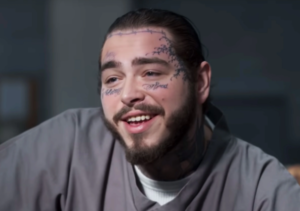 Фотография Post Malone с татуировками на лице, шее и руках. Видны надписи "Always" и "Blessed", а также изображение колючей проволоки.