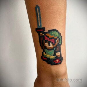 Фото тату на руке с изображением пиксельного персонажа Link из The Legend of Zelda, выполненное в стиле 8-bit.