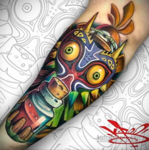 Фото тату: красочный рисунок Маски из Zelda: Majora's Mask на руке, выполненный в ярких цветах и с детализированными узорами.