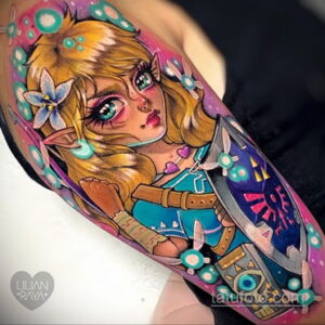Красочное фото тату принцессы Зельды из игры The Legend of Zelda на предплечье. Детализированный рисунок с использованием ярких цветов и светящихся элементов.