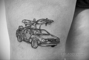 Фото тату на ноге с изображением DeLorean из фильма 'Назад в будущее', выполненного в технике линейной графики.