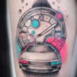 Цветное фото тату на ноге, изображающее автомобиль DeLorean, окруженный часами и яркими брызгами краски.