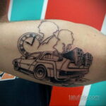 Черно-белая татуировка DeLorean с часами и силуэтом человека, символизирующая путешествия во времени и ностальгию.