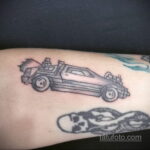 Черно-белое фото тату с изображением DeLorean из фильма «Назад в будущее» и черепа на руке.