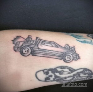 Черно-белое фото тату с изображением DeLorean из фильма «Назад в будущее» и черепа на руке.