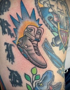 Фото тату на плече с изображением кроссовок Nike MAG из фильма 'Назад в будущее'. Яркий и детализированный рисунок в стиле old school.
