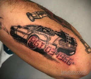 Цветная татуировка на руке с изображением DeLorean из фильма 'Назад в будущее' и надписью '88T031986'.