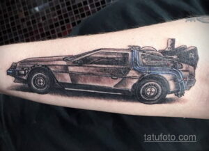 Детализированная черно-серая татуировка на руке с изображением DeLorean из фильма 'Назад в будущее', с реалистичной проработкой деталей и теней.