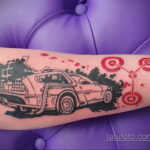 Фото тату: Минималистичная татуировка DeLorean на руке. Черно-белый рисунок с красными кругами. Простой и стильный дизайн.