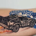 Фото тату: Татуировка DeLorean с изображением молний и огня. Черно-белый рисунок с яркими акцентами. Динамичный стиль.