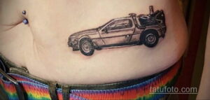 Фото тату: Черно-белый рисунок DeLorean на женском боку. Детализированная проработка автомобиля, реалистичное изображение, минималистичный стиль.