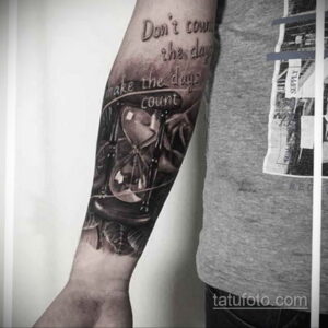 Фото тату с изображением песочных часов и надписью 'Don't count the days, make the days count' на предплечье.