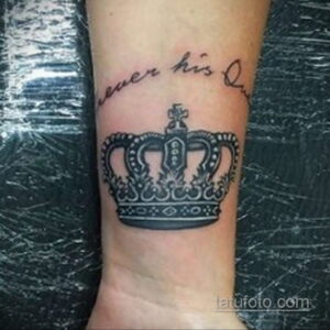 Фото татуировки на предплечье: черная корона с надписью 'Never His Queen'. Символ независимости и самодостаточности.