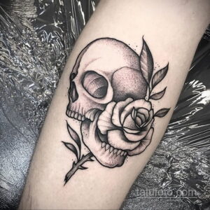 Фото тату черепа и розы, выполненное в стиле blackwork с использованием только черных оттенков. Классический и минималистичный рисунок татуировки.