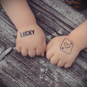 Фото тату на руках пары: надпись 'LUCKY' на одной руке и контур сердца со стрелой на другой. Минималистичный дизайн, символизирующий удачу и любовь.