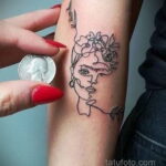Фото минималистичной татуировки лица на руке, выполненной в стиле line art. Тонкие линии, схематичное изображение, идея для женской татуировки.