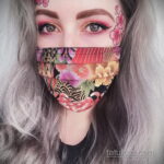 Фото татуировки, выполненной в виде цветочного узора на маске для лица, с использованием ярких цветов и деталей.