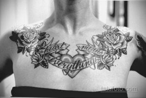 Фото тату на груди с изображением роз, бабочек и надписи 'Heart means everything'. Выполнено в черно-белом стиле, с акцентом на детализацию.