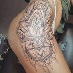 Фото тату: сложная мандала в стиле dotwork на женском бедре. Детализированный рисунок татуировки с геометрическими узорами.