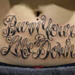 Фото тату на животе: надпись "Burn Your Life Down" в готическом стиле. Черная татуировка, выражающая бунтарский дух.