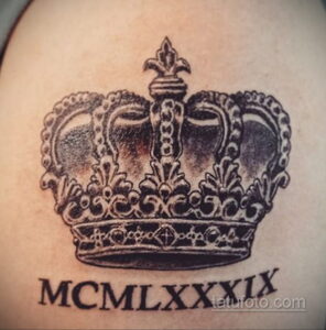 Фото тату в виде короны с римскими цифрами MCMXLXXIX, выполненной в технике blackwork. Детализированный рисунок на коже.