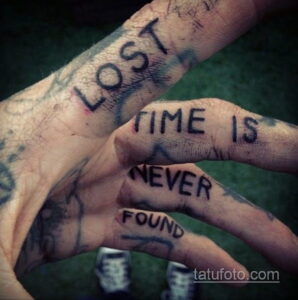Фото тату: фраза "Lost time is never found" нанесена на руку в рукописном стиле. Черные чернила и небрежный шрифт создают эффект временности и меланхолии.