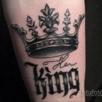 Фото тату на руке, изображающее корону и надпись "Her King". Выполнено в черно-серых тонах с детализированной проработкой.