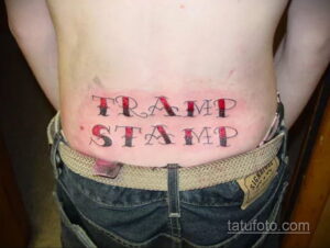Фото татуировки 'Tramp Stamp' на пояснице женщины: надпись 'Tramp Stamp' в красном цвете, выполненная в традиционном стиле.