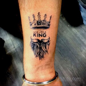 Фото тату короны и надписи "Live Like a King" на запястье мужчины. Рисунок выполнен в черно-белой графике.