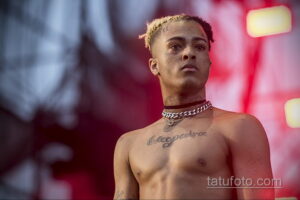 Фото тату XXXTentacion с надписью на груди и шее. Черная татуировка на теле рэпера, демонстрирующая его стиль и индивидуальность.