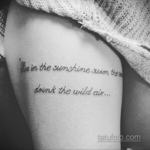 Фото тату с изображением текстовой надписи "Live in the sunshine swim the sea drink the wild air..." на руке. Элегантный шрифт и минималистичный дизайн.