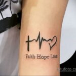 Фото тату на руке с изображением креста, сердечной волны и сердца. Подпись 'Faith. Hope. Love'. Минималистичный стиль.