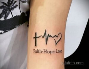 Фото тату на руке с изображением креста, сердечной волны и сердца. Подпись 'Faith. Hope. Love'. Минималистичный стиль.